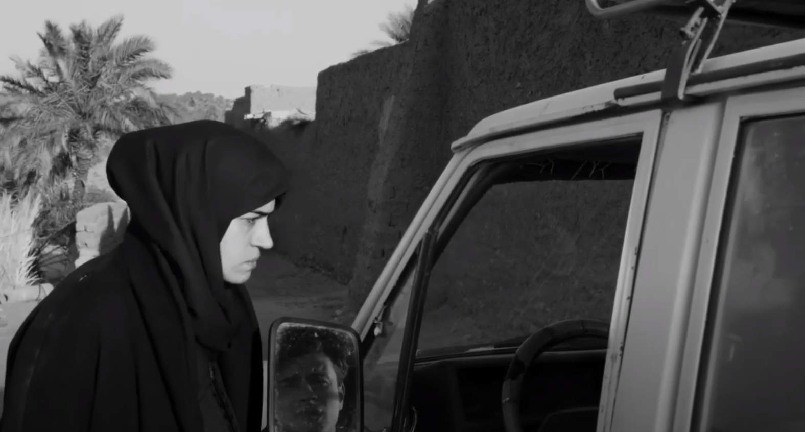 woman wearing burka speaking to someone in a car