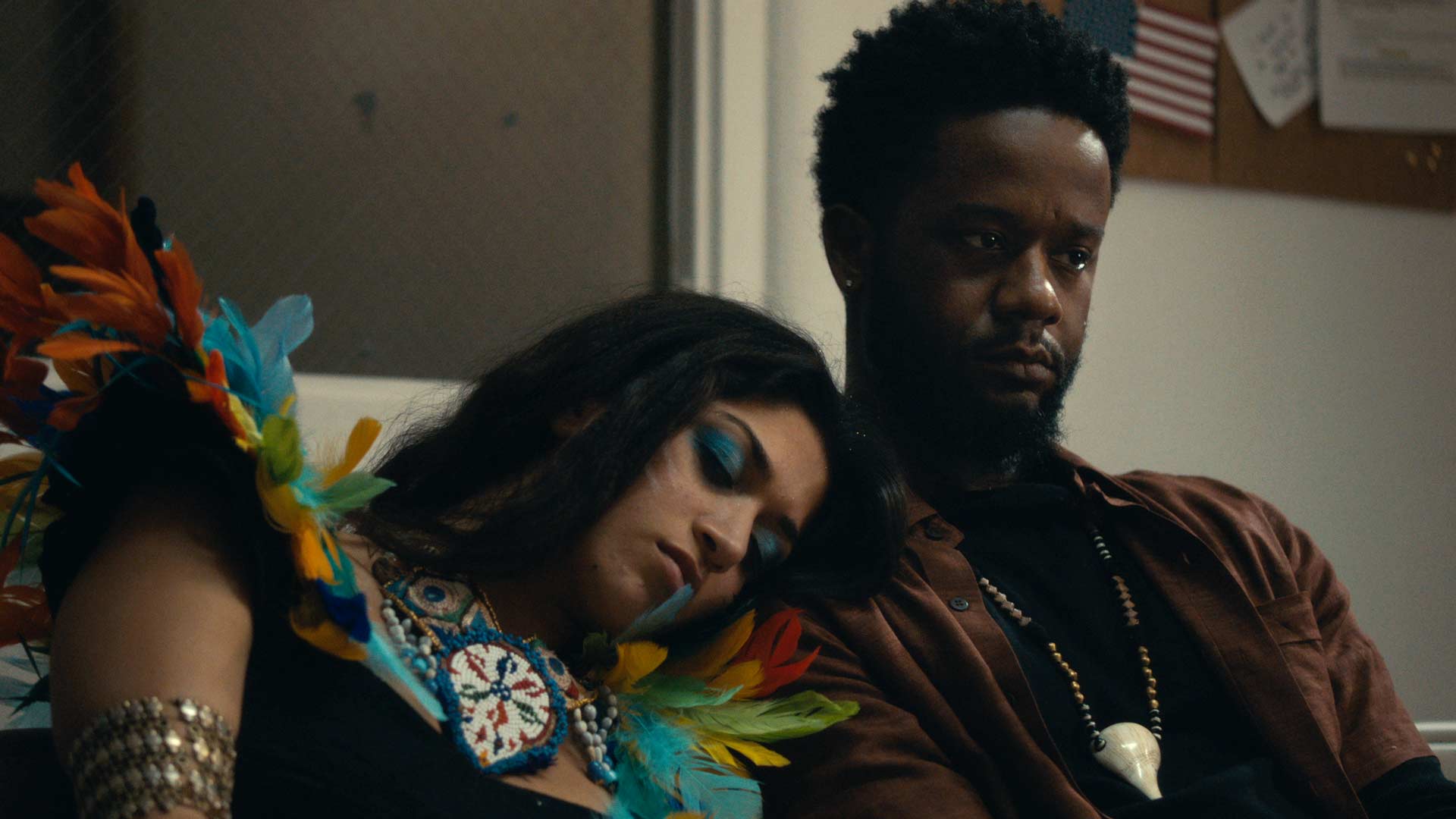 woman with colourful dress and strong makeup rests head on mans shoulder