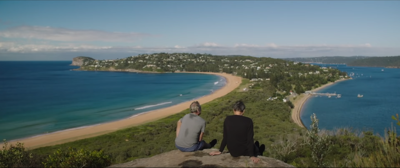 sitting on top of a hill looking out at the ocean and beach