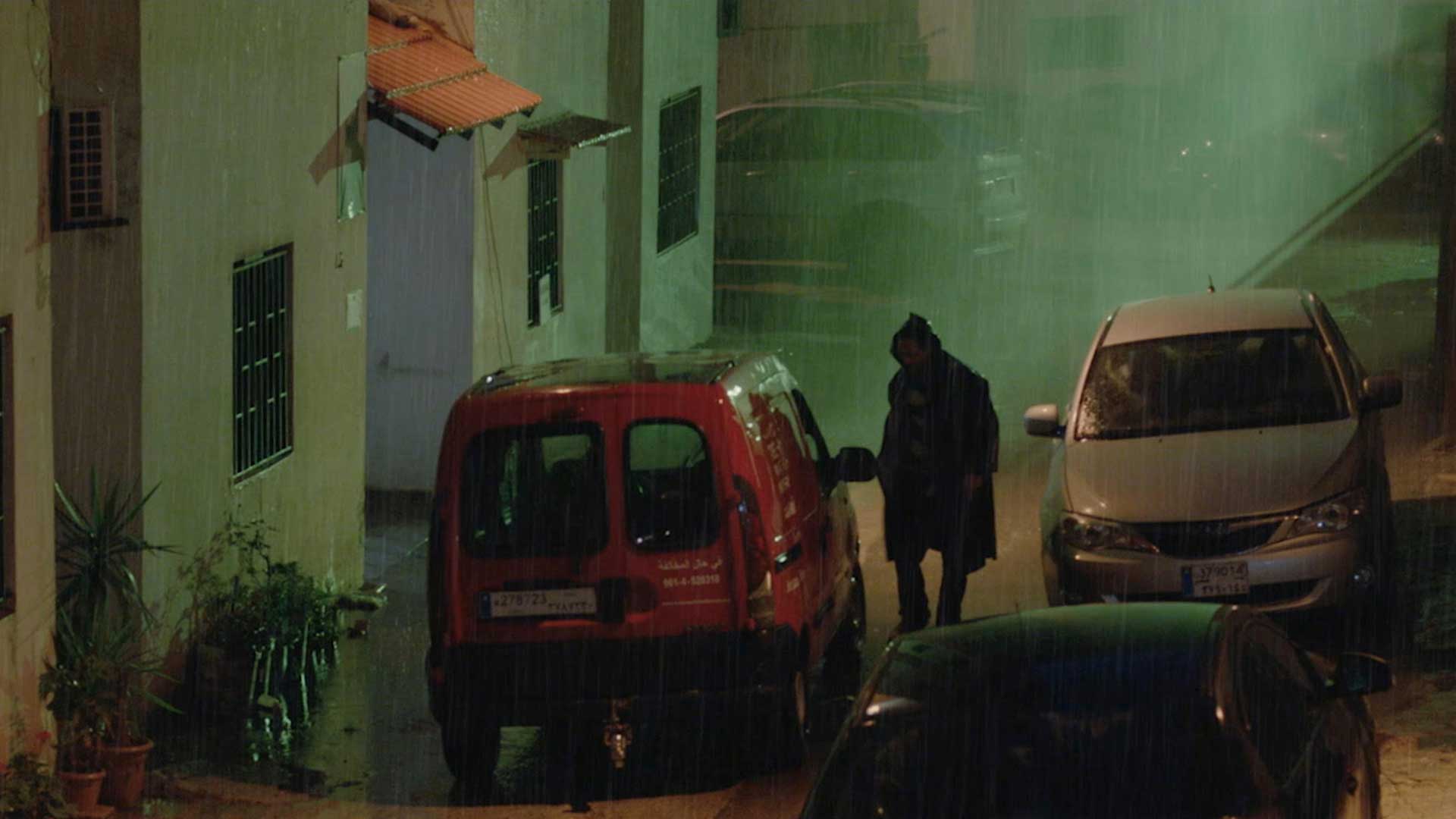 man next to a red car in the dark.